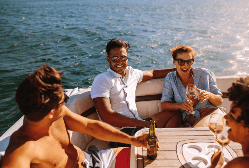 Image is of a group of smiling friends drinking on a boat, concept of boating under the influence in Florida