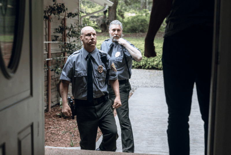 Image is of two police officers at the front door of a home with homeowner in the door way, concept of how to handle false accusations of domestic violence in Gainesville