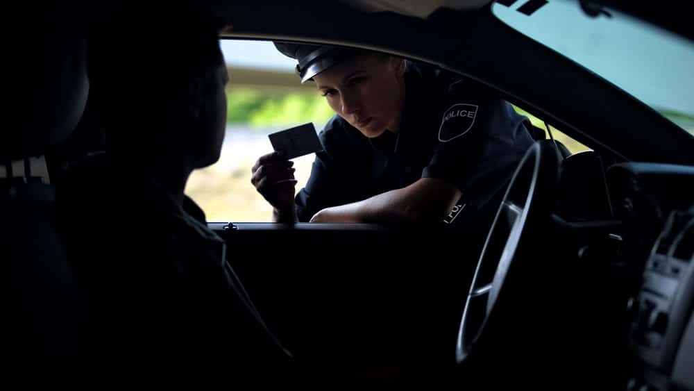 Police officer inspecting driver license during a traffic stop related to DUI for college students in Florida investigation.
