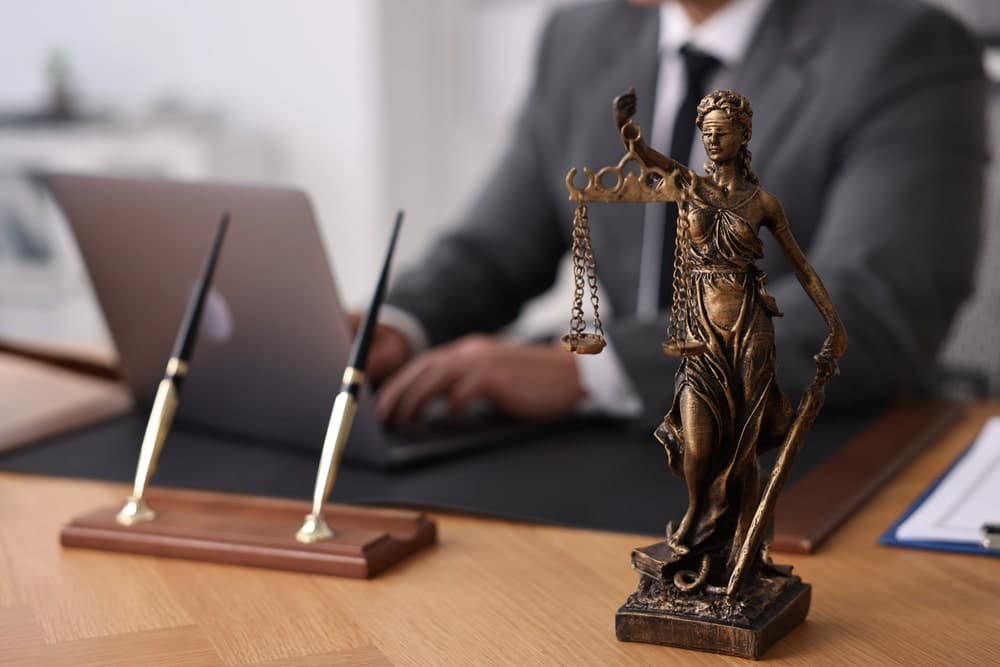 Lawyer working at desk with Lady Justice statue after an underage drinking arrest at UF.