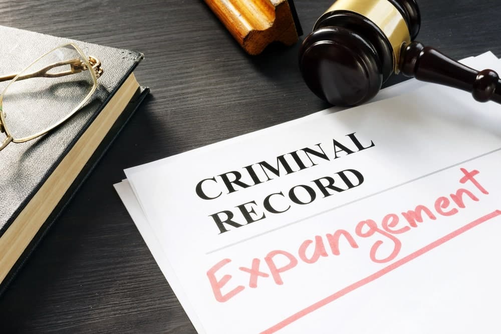 Image shows criminal record files with the word expungement highlighted alongside a gavel and glasses, concept of clearing records that could impact a graduate application after a DUI arrest.