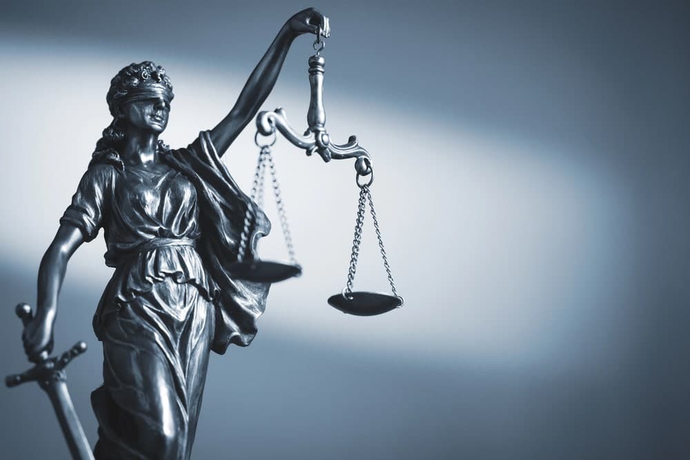 Image is of a Lady Justice statue holding balanced scales, symbolizing legal issues that arise when drivers refuse a breath test in Florida.