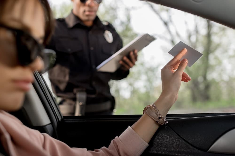 Image is of a driver handing identification to a police officer during a traffic stop, representing how a DUI stay on your record begins with law enforcement interaction in Florida.