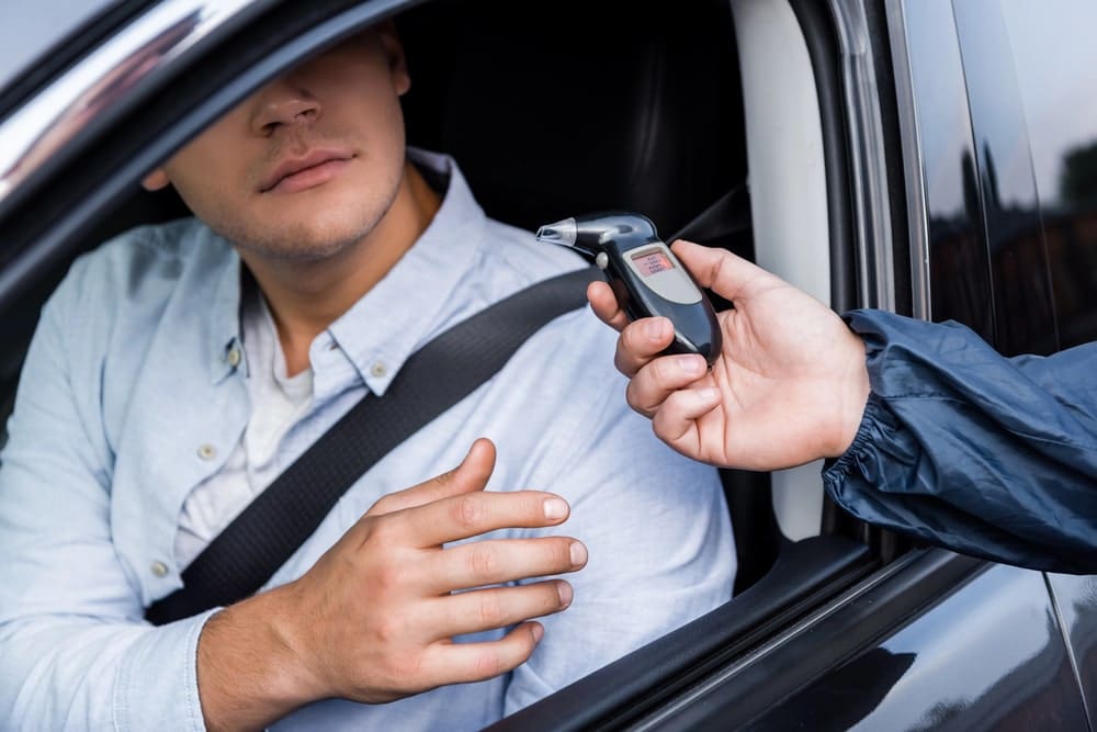 Image is of a police officer administering a breathalyzer test during a traffic stop, representing DUI charges that may affect a UF student’s academic and legal future.