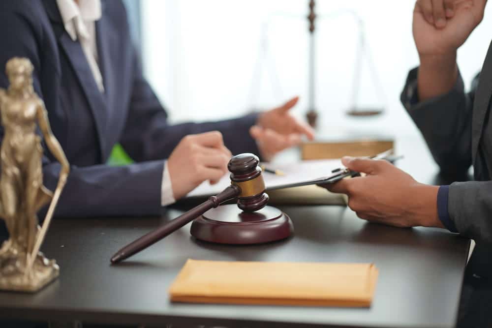Image is of a client consulting with an attorney over legal paperwork, reflecting the court process required for expungement in Florida.