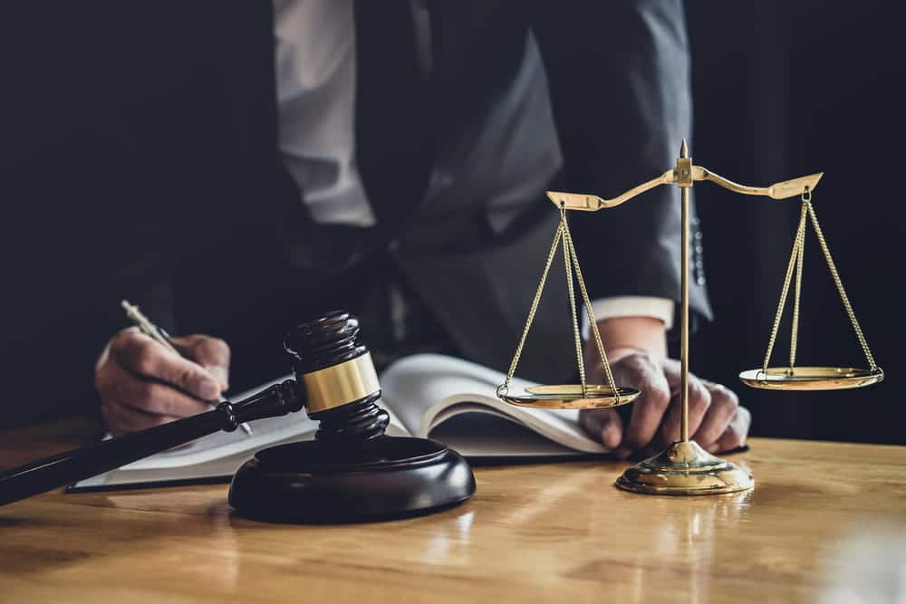 Image of a legal professional signing documents next to a gavel and scales of justice, illustrating the process of seeking a court-ordered expungement.