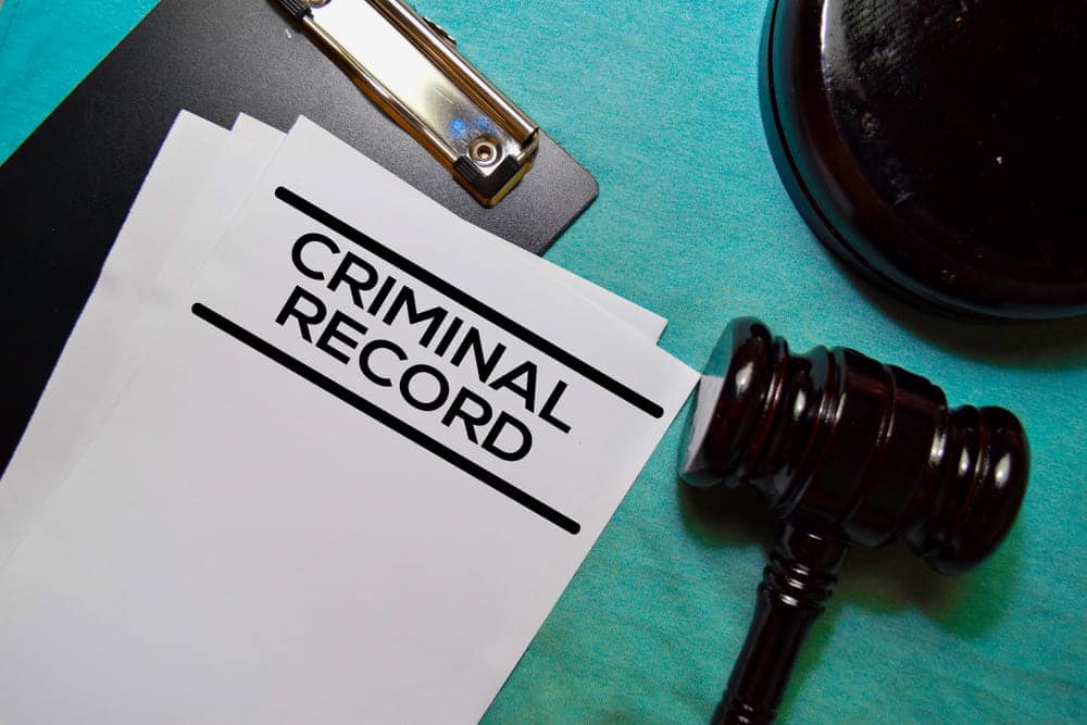 Image is of court documents labeled criminal record placed beside a judge’s gavel, concept of administrative expungement and the legal process used to remove inaccurate arrest records.