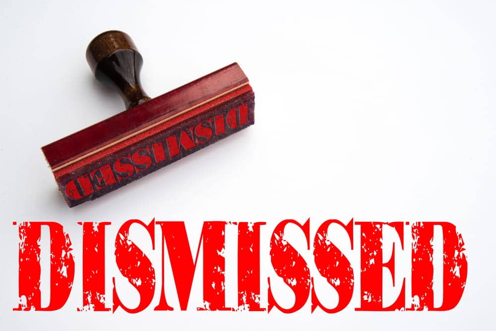 Image is of a red dismissed stamp on a document, representing dismissed charges and legal case outcomes