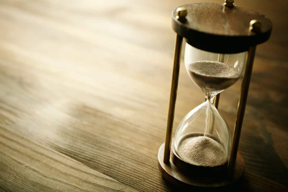 Image is of a close-up hourglass on a wooden surface, representing the waiting period for a court-ordered expungement