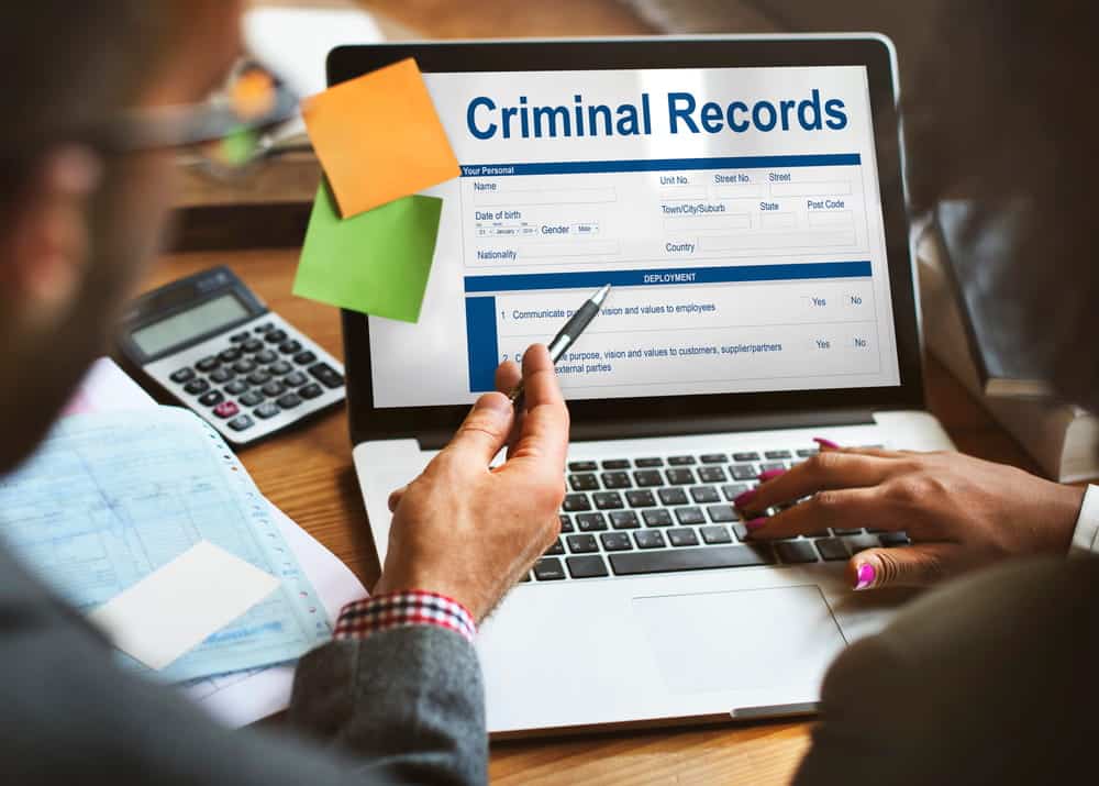 Image is of a professional reviewing criminal records on a laptop, concept of administrative expungement process and record verification